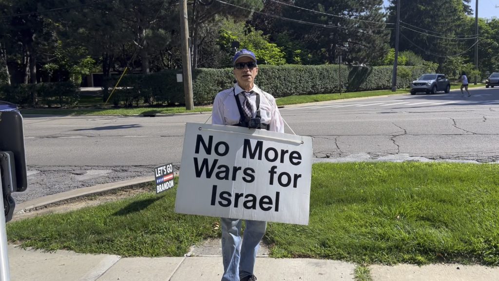 a man holding a sign reading "No More Wars for Israel" outside a synagogue in Ann Arbor, MI