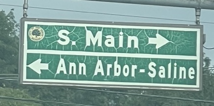 Weathered street sign show S. Main street to the right, and Ann Arbor-Saline road to the left