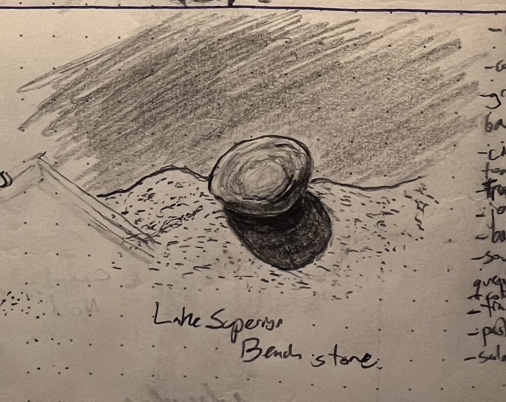 A pencil sketch of a stone on a sandy outcrop over water. The stone is brightly lit, and its shadow is sharp and deep.