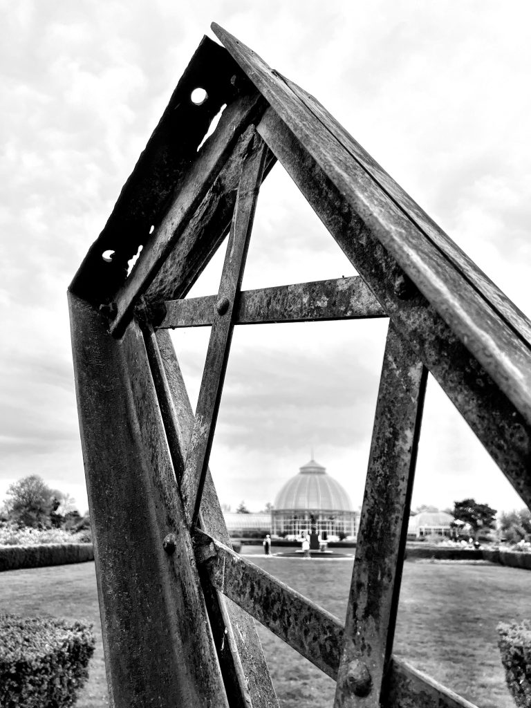 A picture of some scrap metal memorialized on Belle Isle (Detroit, MI). The domed greenhouse of the Belle Isle Conservatory is visible on the background.